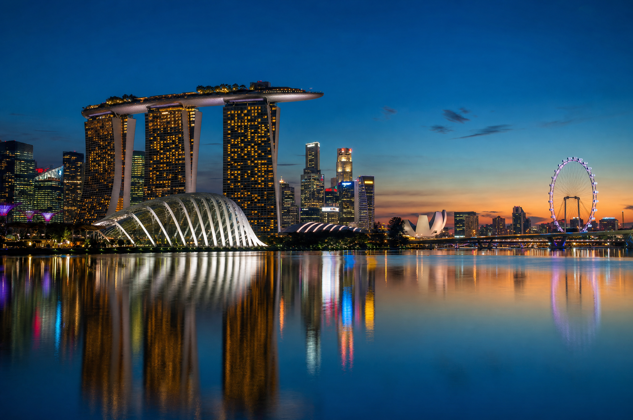 Marina Bay Sands illuminated at blue hour with reflections on the harbor water